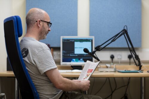 Photo of a man being recorded reading a book